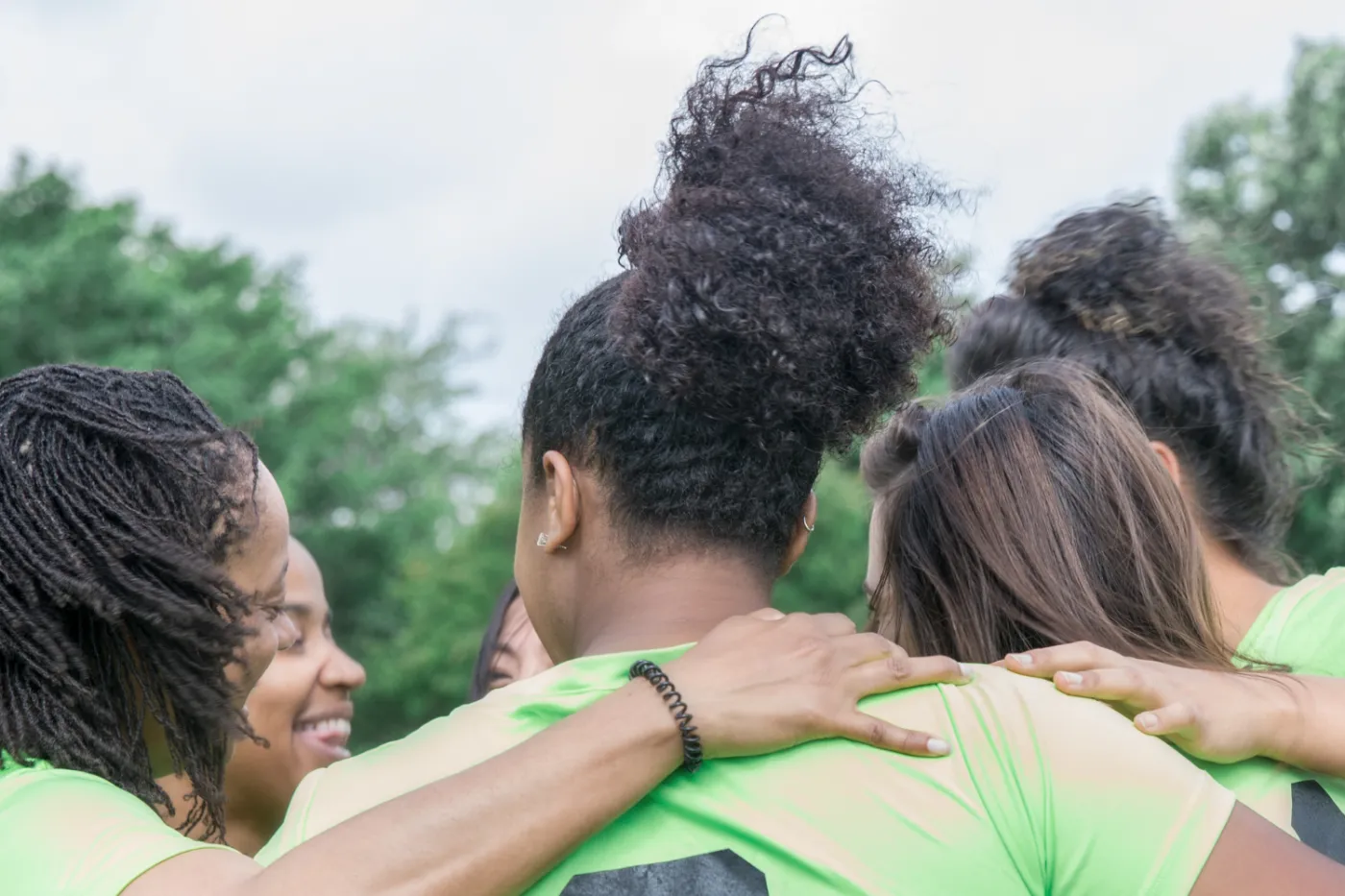 Teamkreis (Foto: Canva) Frauen unterschiedlicher Hautfarben in Trikots bilden einen Teamkreis.